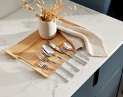 Elegantes Besteckset King 30-tlg. auf einem Holztablett, von oben fotografiert, mit dekorativer Vase und Stoffserviette.