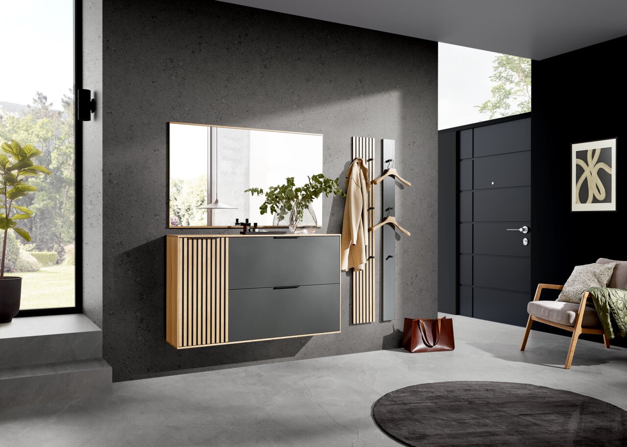 Dieter Knoll Paneel-Leiste RIVA Moderner Eingangsbereich mit hängendem Schuhschrank, großem Spiegel und Garderobenpaneel in Holzoptik. Perspektive von schräg vorne.