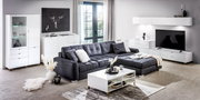 Modernes Wohnzimmer mit weißem Sideboard, Vitrine und Couchtisch, grauem Sofa und Wandregal, seitliche Perspektive