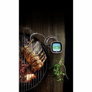 Digitales Bratenthermometer neben einem gegrillten Fleischstück auf einem Grill, aus der Vogelperspektive aufgenommen.
