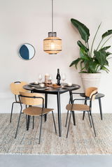 Esszimmer mit modernem Stuhl-Set aus Holz und Metall, runder Tisch, hängende Lampe und große Pflanze, seitliche Perspektive