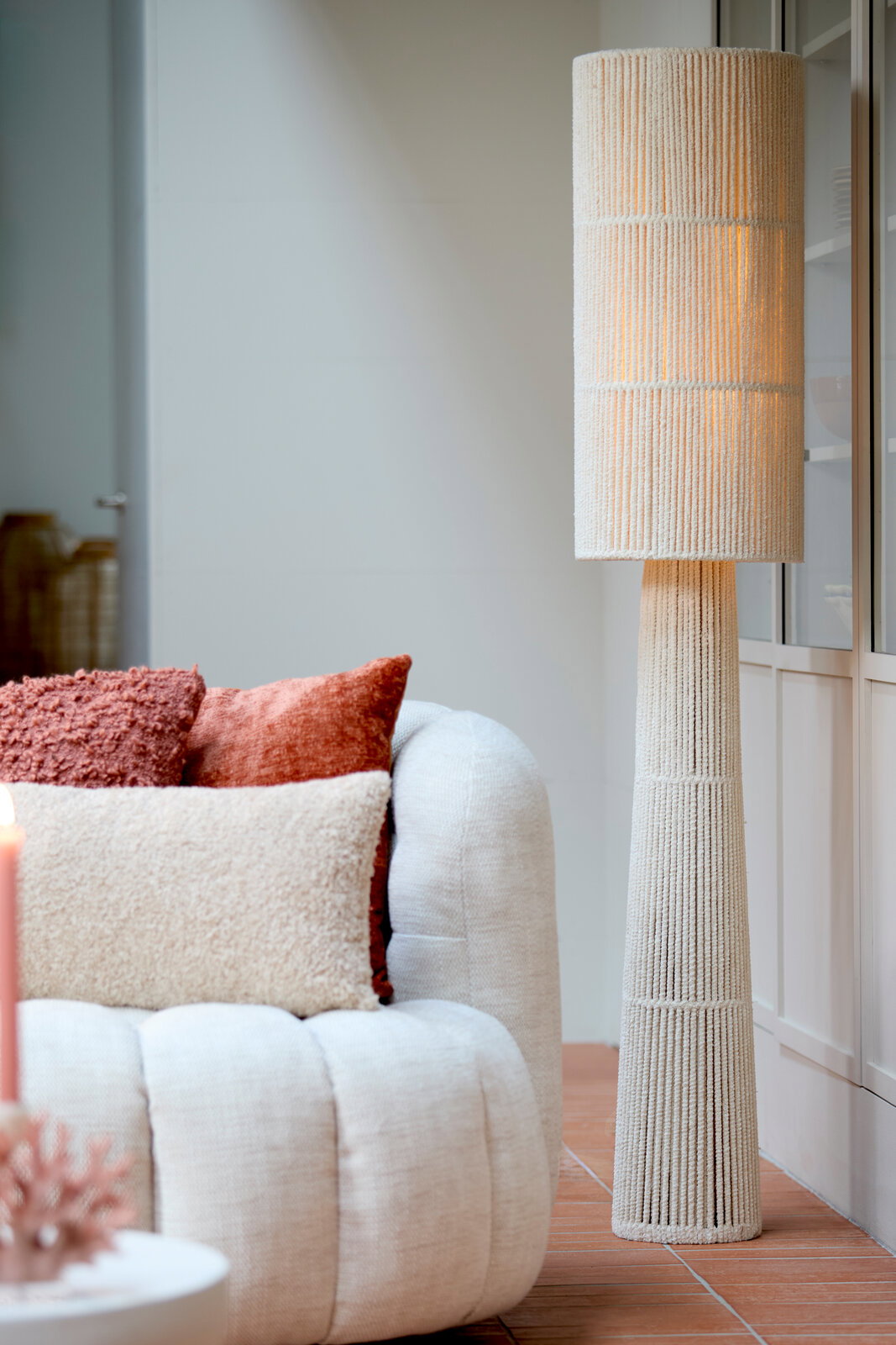 Stehleuchte mit texturiertem, zylindrischem Lampenschirm in einem modernen Wohnzimmer, seitliche Perspektive