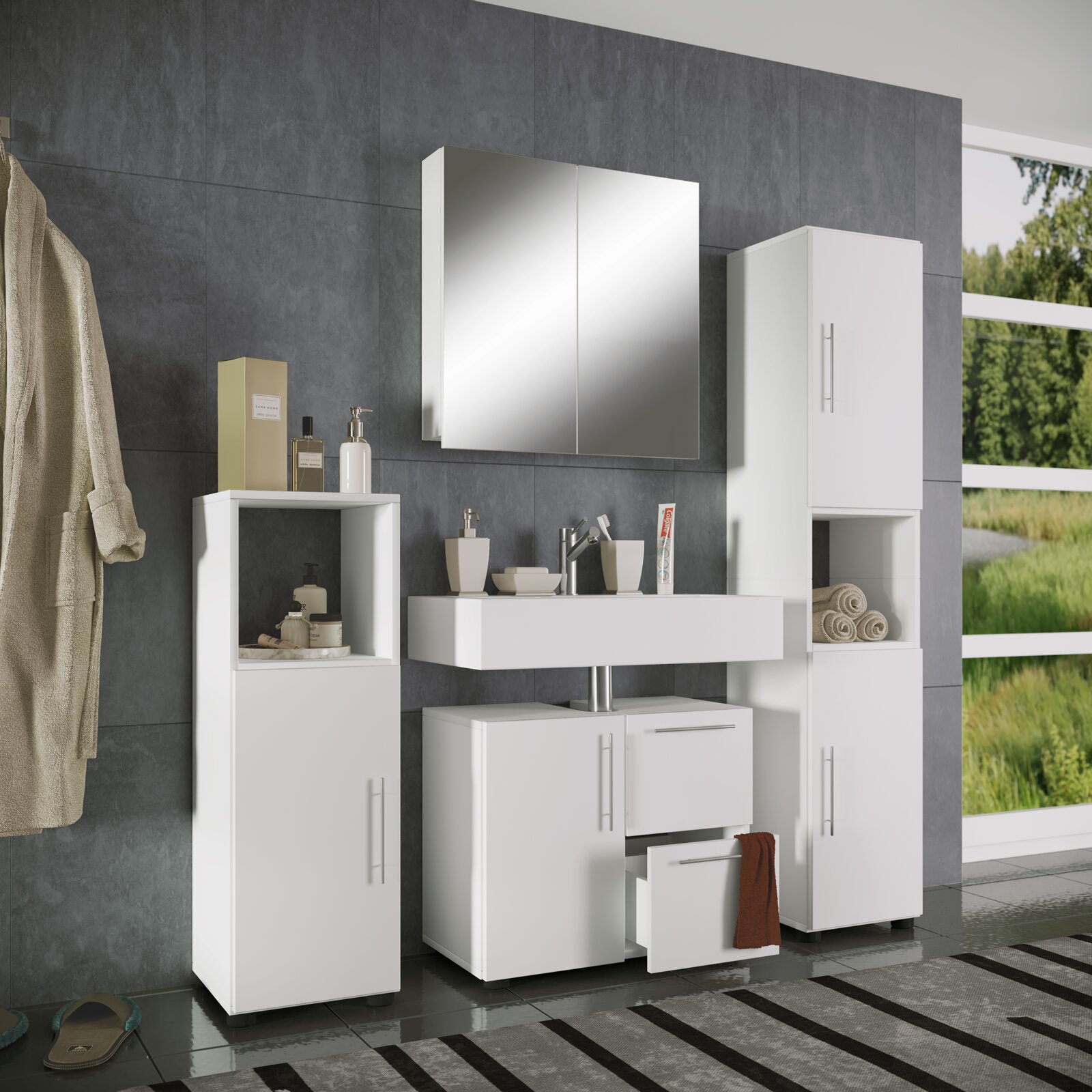 Modernes weißes Badezimmermöbel-Set mit Waschtischunterschrank, Spiegelschrank und zwei Hochschränken vor grauer Fliesenwand, Frontansicht in leichter Schrägperspektive von links.