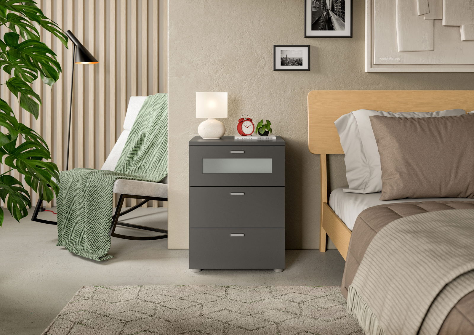 Moderne Nachtkommode XENO in dunklem Grau mit drei Schubladen, dekoriert mit einer Lampe und einem Wecker, seitliche Perspektive.