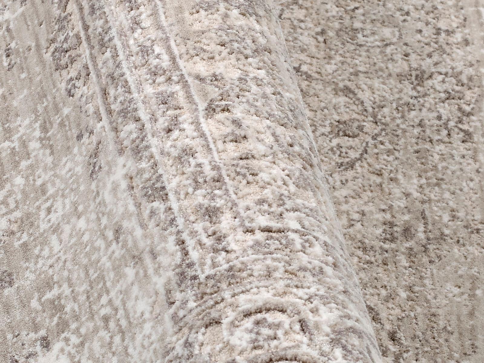 Nahaufnahme eines Designer-Teppichs mit detaillierter Textur und Muster in neutralen Tönen, seitliche Perspektive