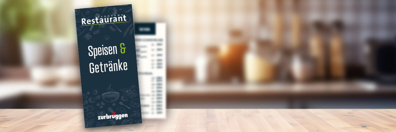 Speisekarte „Speisen & Getränke“ des Panorama Restaurants auf Tresen vor unscharfem Küchenhintergrund.