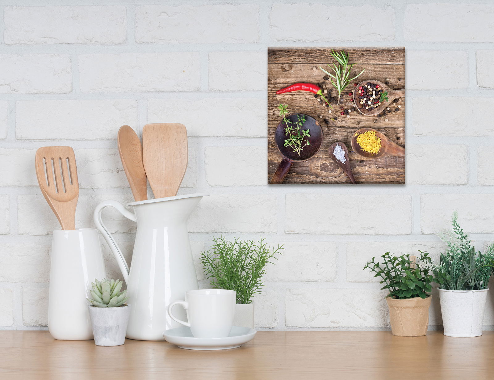 Leinwandbild mit Kräutern der Provence, aus der Perspektive einer Küchenarbeitsplatte betrachtet, zeigt Gewürze und Kräuter auf Holzlöffeln vor einer weißen Ziegelwand.