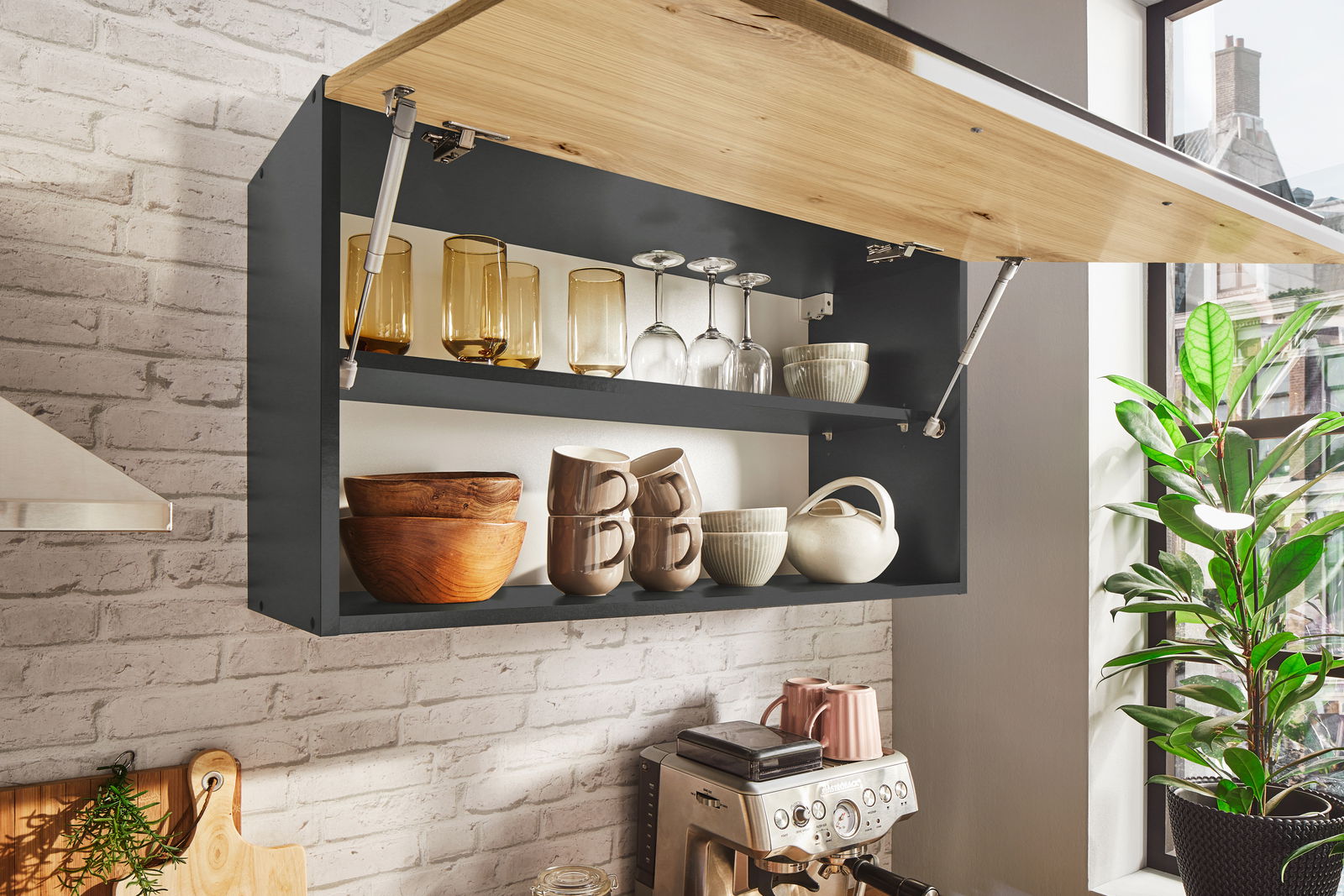 Küchenblock mit geöffnetem Hängeschrank, gefüllt mit Gläsern, Tassen und Schalen, aus seitlicher Perspektive fotografiert.