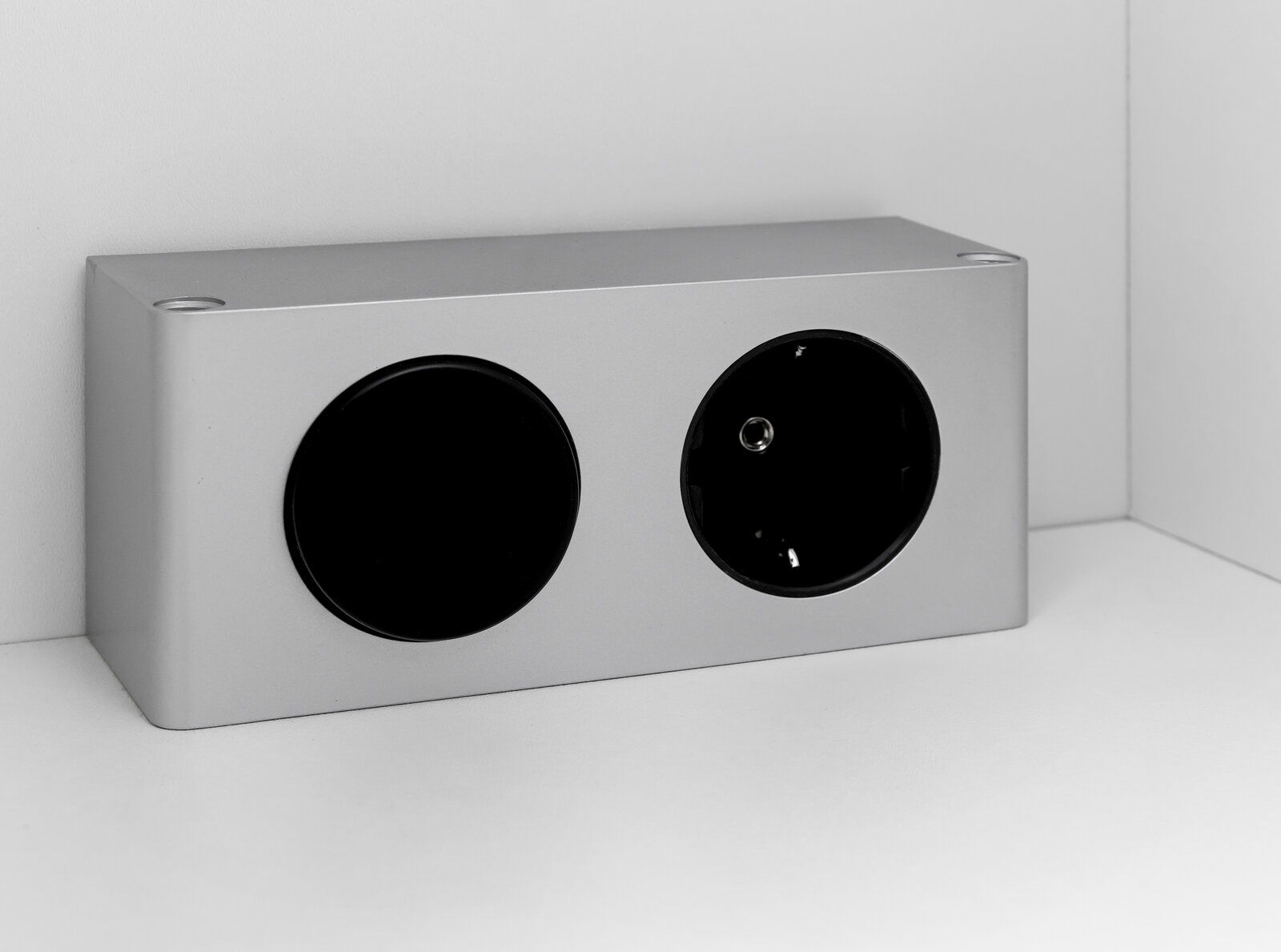 Silberne Steckdose mit schwarzem Abdeckknopf, seitliche Perspektive