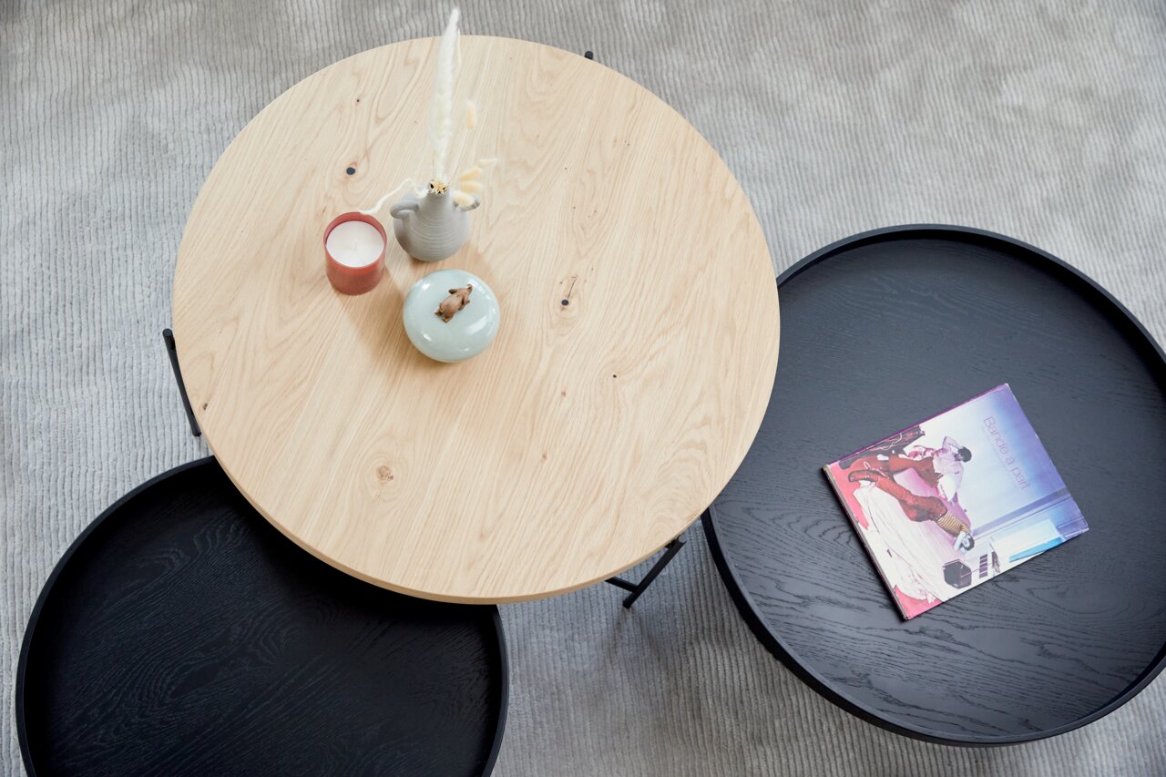 Runder Couchtisch aus Holz und Metall, von oben fotografiert, mit Dekorationen und einem Buch.
