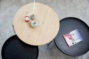 Runder Couchtisch aus Holz und Metall, von oben fotografiert, mit Dekorationen und einem Buch.