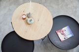 Runder Couchtisch aus Holz und Metall, von oben fotografiert, mit Dekorationen und einem Buch.