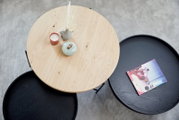 Ronde salontafel van hout en metaal, gefotografeerd van bovenaf, met decoraties en een boek.