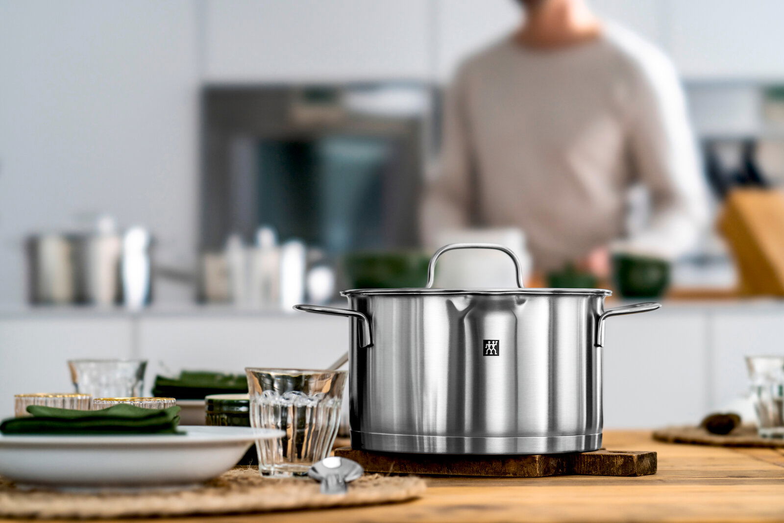 Edelstahlkochtopf aus dem 5-teiligen Topfset True Flow, frontal auf einem Holztisch in einer modernen Küche platziert.