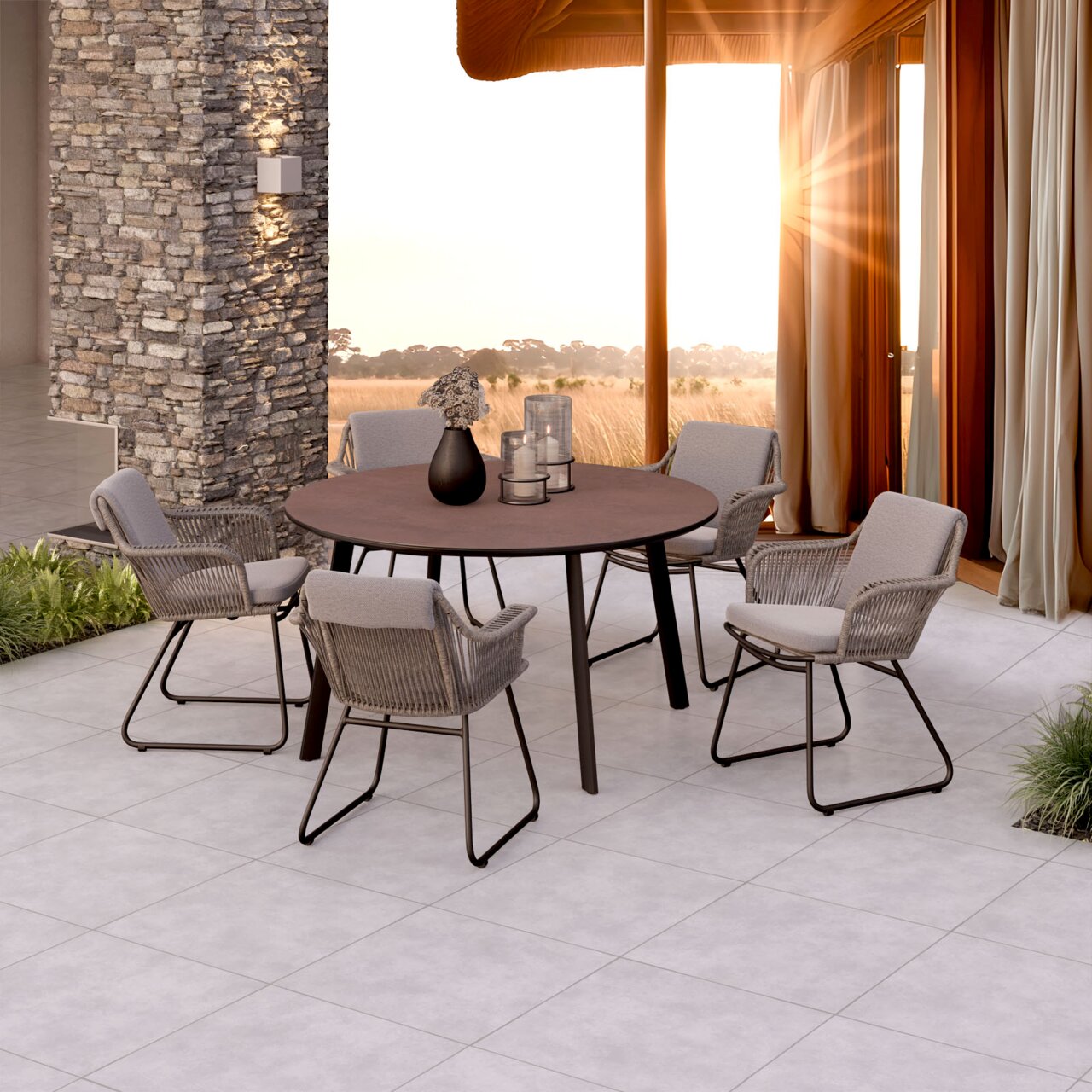 Outdoor-Essgruppe mit rundem Tisch und vier gepolsterten Seil-Geflechtstühlen auf moderner Terrasse, seitliche Perspektive in leichter Aufsicht
