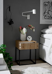 Moderne Nachtkommode aus Holz mit schwarzem Metallgestell, dekoriert mit einer Pflanze und einer Uhr, seitliche Perspektive.