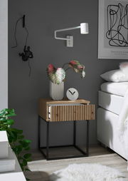 Moderne Nachtkommode aus Holz mit schwarzem Metallgestell, dekoriert mit einer Pflanze und einer Uhr, seitliche Perspektive.