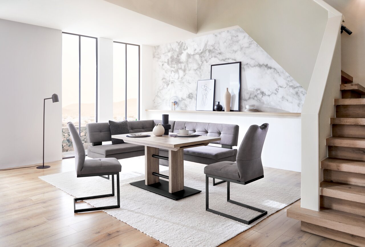 Dieter Knoll Schwingstuhl LIMONE Moderne Essgruppe mit Eckbank und Freischwinger-Stühlen in einem hellen Raum mit Holzfußboden, seitliche Perspektive.