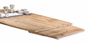 Nahaufnahme eines Esstisches aus hellem Holz mit natürlicher Maserung, gedeckt mit Geschirr und Gläsern, aus seitlicher Perspektive.
