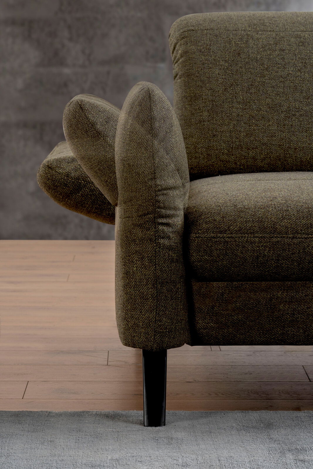 Nahaufnahme einer grünen Sofaecke mit Armlehne und schwarzem Bein, seitliche Perspektive.