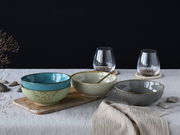 Drei stilvolle Smoothie-Schalen in verschiedenen Farben auf einem Tisch, mit einer seitlichen Perspektive aufgenommen.