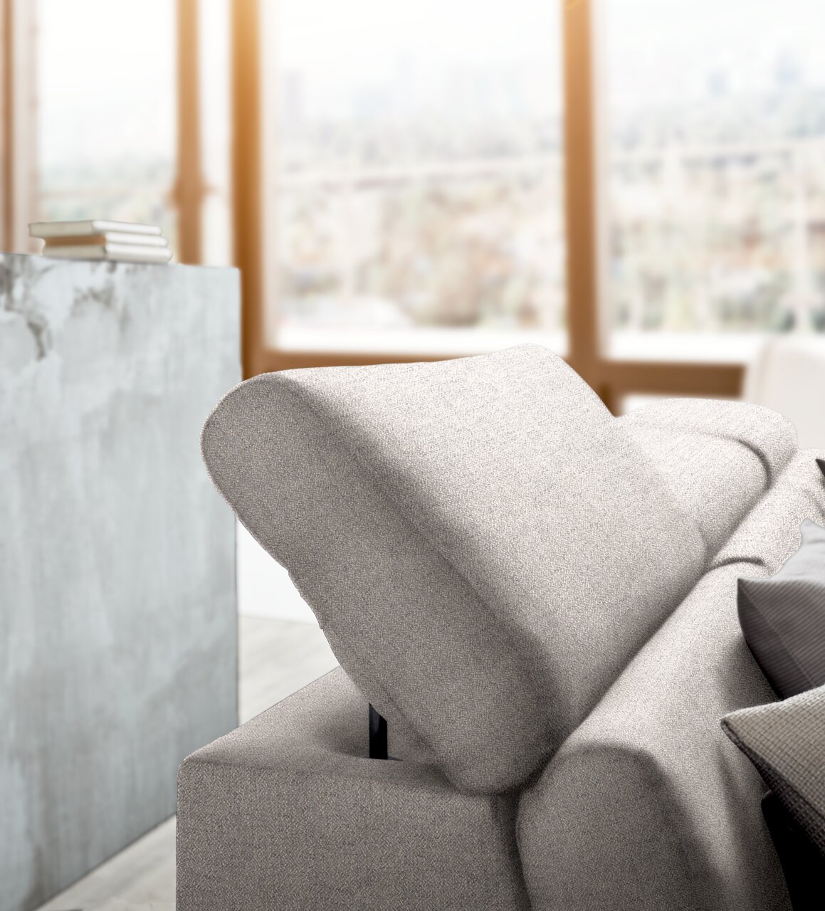 Nahaufnahme einer modernen, hellgrauen Rundecke mit verstellbarer Rückenlehne in einem hellen Raum mit großen Fenstern.