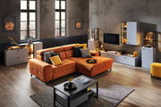Moderne Wohnzimmermöbel in einem stilvollen Raum mit einem großen orangefarbenen Sofa, umgeben von weißen und schwarzen Schränken und einem Couchtisch. Perspektive: Frontalansicht des Wohnzimmers.