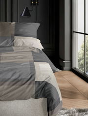 Bettwäsche-Set irisette WAVE in Grau- und Beigetönen, auf einem Bett in einem modernen Schlafzimmer mit Holzfußboden und großem Fenster, seitliche Perspektive.