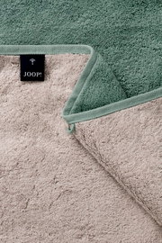 Gästetuch in zwei Farben, grün und beige, mit einer Nahaufnahme der Textur und einem Joop-Label, aus der Vogelperspektive.