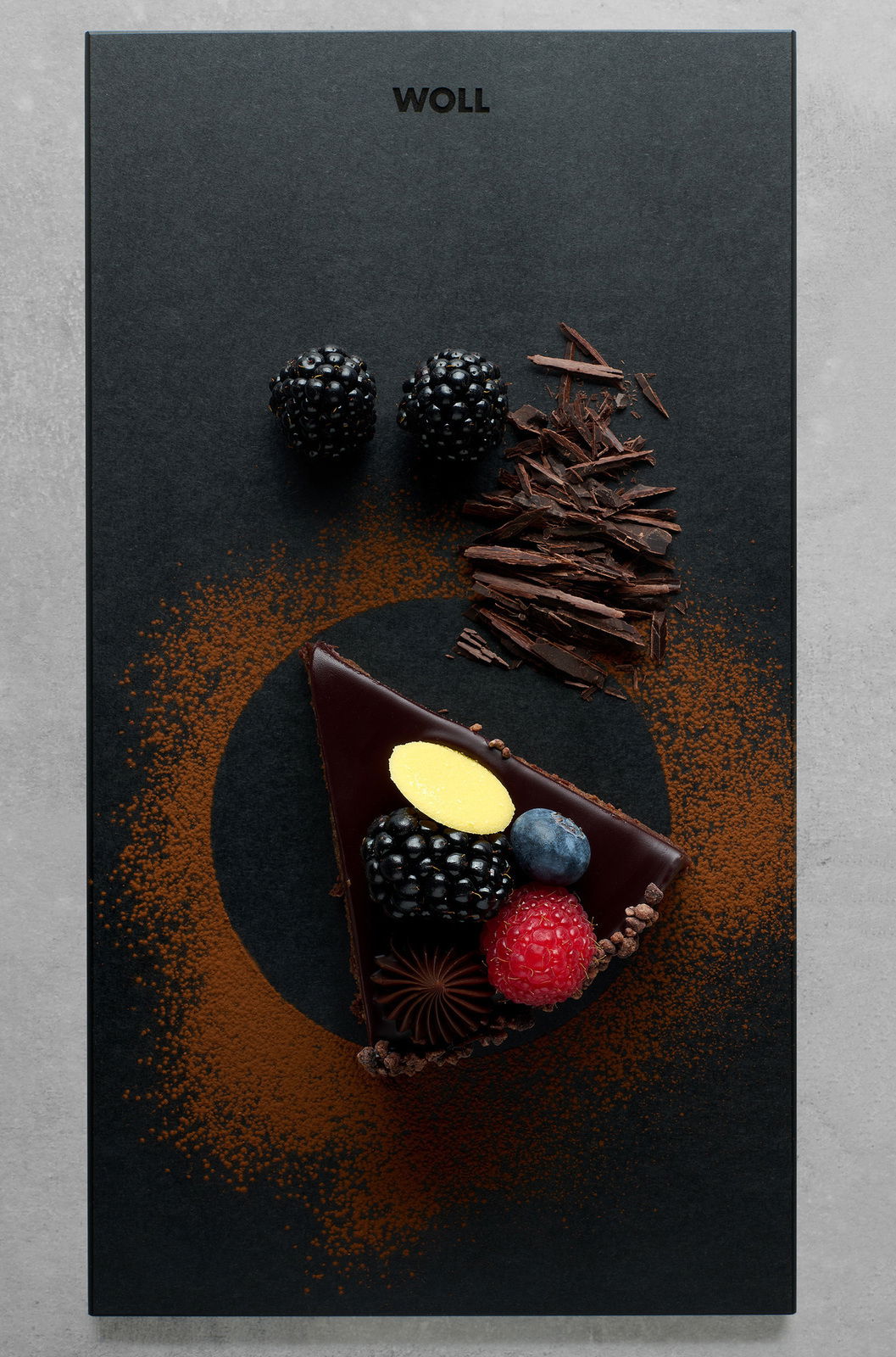 Woll Frühstücksset 2tlg. CULT & SERVE Vogelperspektive auf ein elegantes Frühstücksset mit einer Schieferplatte, dekoriert mit einem Stück Schokoladenkuchen, frischen Beeren und Schokoladenspänen.