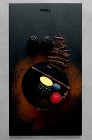 Vogelperspektive auf ein elegantes Frühstücksset mit einer Schieferplatte, dekoriert mit einem Stück Schokoladenkuchen, frischen Beeren und Schokoladenspänen.