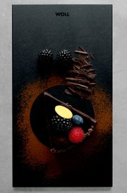 Vogelperspectief op een elegante ontbijtset met een leisteenplaat, versierd met een stukje chocoladetaart, verse bessen en chocoladeschilfers.