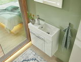 Modernes Gästebad mit weißem Waschbecken und Unterschrank, seitliche Perspektive. Dekorative Vase mit Pflanzen und Handtuchhalter an der Wand.