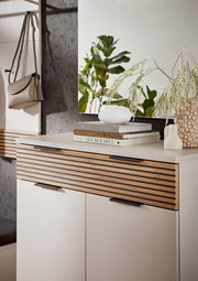 Moderner Schuhschrank mit Holzlamellen-Design, dekoriert mit Büchern und Vasen, seitliche Perspektive