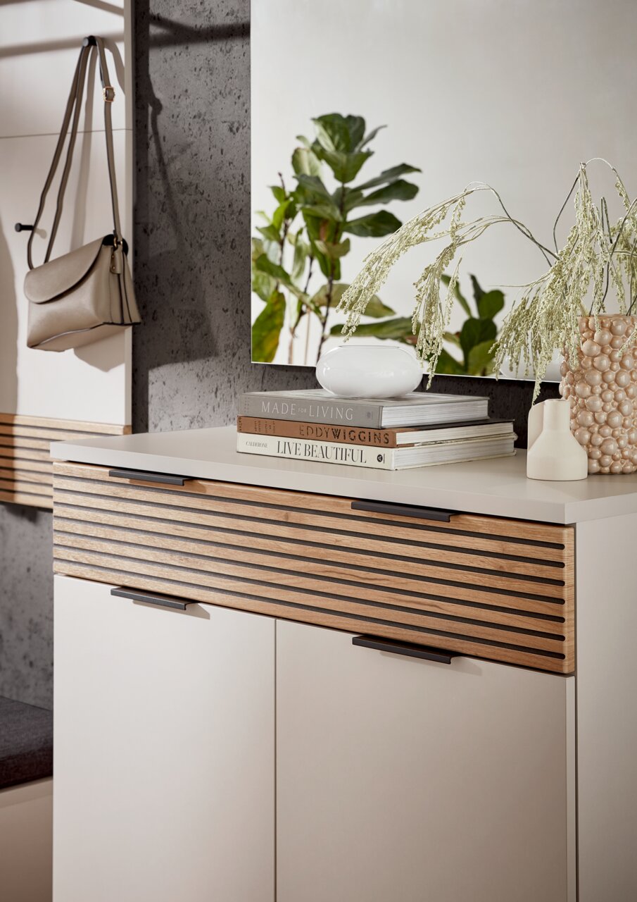 Moderner Schuhschrank mit Holzlamellen-Design, dekoriert mit Büchern und Vasen, seitliche Perspektive