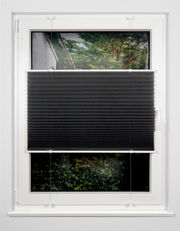 Schwarzes Plissee am Fenster, halb heruntergelassen, mit Blick auf einen Garten im Hintergrund.