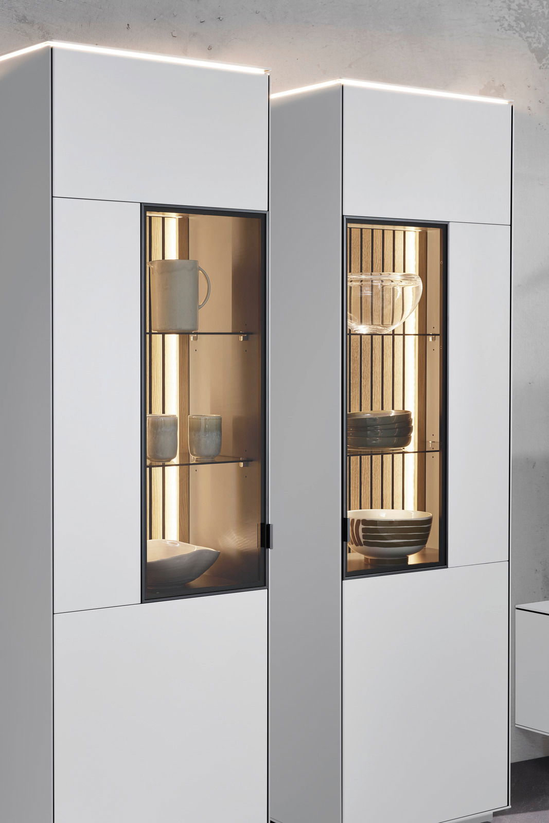 Moderne Vitrine mit Glasfronten, beleuchtetem Innenraum und stilvoller Präsentation von Geschirr, seitliche Perspektive