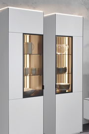 Moderne Vitrine mit Glasfronten, beleuchtetem Innenraum und stilvoller Präsentation von Geschirr, seitliche Perspektive