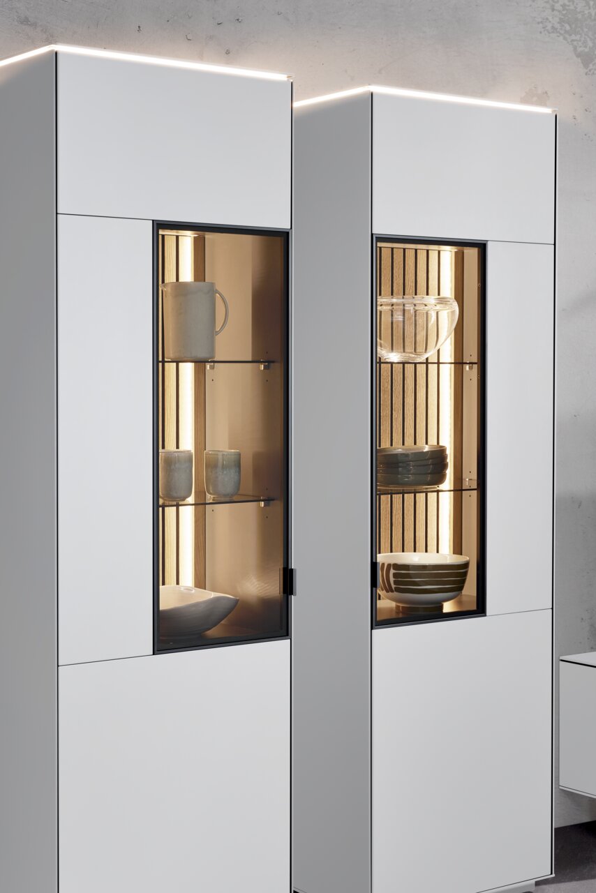 Moderne Vitrine mit Glasfronten, beleuchtetem Innenraum und stilvoller Präsentation von Geschirr, seitliche Perspektive