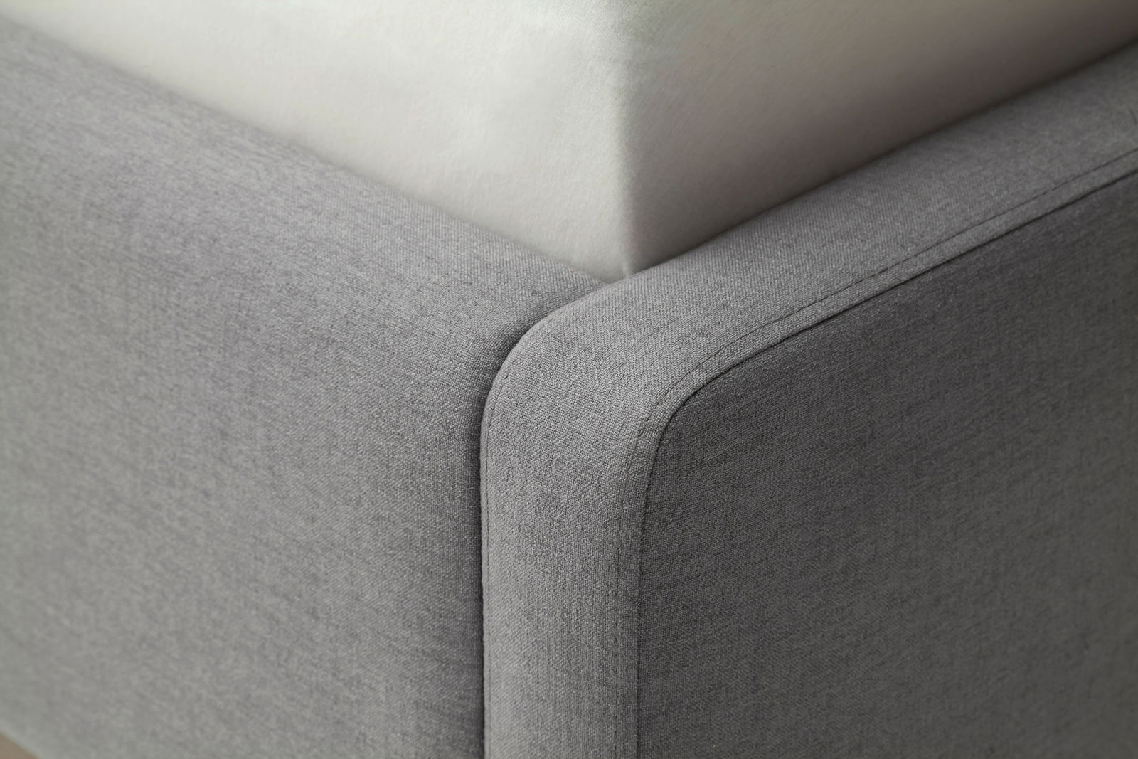 Nahaufnahme einer Ecke eines grauen Polsterbetts mit weicher Textur, von oben betrachtet.