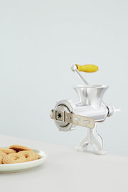 Fleischwolf Nr. 8 aus Metall mit gelbem Holzgriff, seitliche Perspektive, neben einem Teller mit Keksen.