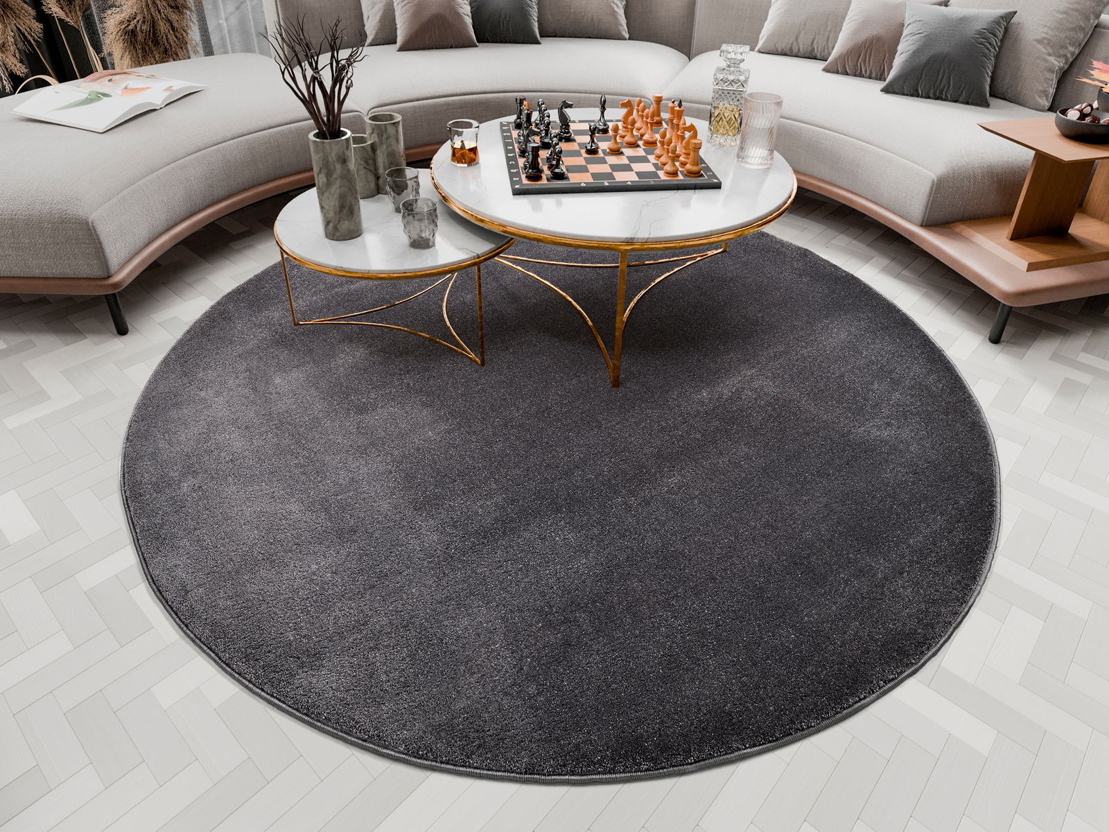 Runder, dunkelgrauer Uni-Teppich in einem modernen Wohnzimmer, von oben betrachtet, mit einem eleganten Couchtisch und einem Schachspiel darauf.