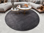 Runder, dunkelgrauer Uni-Teppich in einem modernen Wohnzimmer, von oben betrachtet, mit einem eleganten Couchtisch und einem Schachspiel darauf.