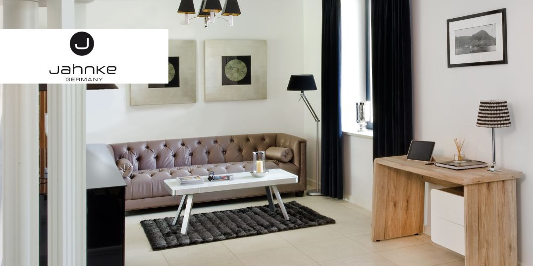 Modernes Wohnzimmer mit einem Sofa in Beige, einem hellen Holzschreibtisch, Kunstwerken und einer schwarzen Stehlampe.