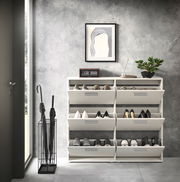 Schuhkipper mit sechs Fächern, frontal fotografiert, in einem modernen Raum mit grauer Wand, dekoriert mit einer Pflanze, einem Bild und einer Uhr.