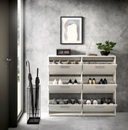 Schuhkipper mit sechs Fächern, frontal fotografiert, in einem modernen Raum mit grauer Wand, dekoriert mit einer Pflanze, einem Bild und einer Uhr.