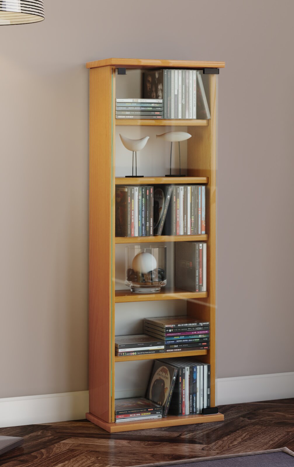 Schmales, hohes Holzregal in hellem Holzton mit mehreren Fächern, gefüllt mit CDs, Büchern und Deko, frontal aus leichter Seitenperspektive fotografiert vor grauer Wand.