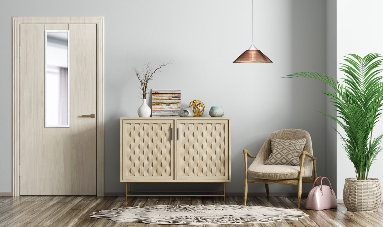 Deurspiegel van ca. 30 x 120 cm, opgehangen aan een houten deur in een modern ingerichte kamer met een ladekast, een fauteuil en een plant, gezien van voren.