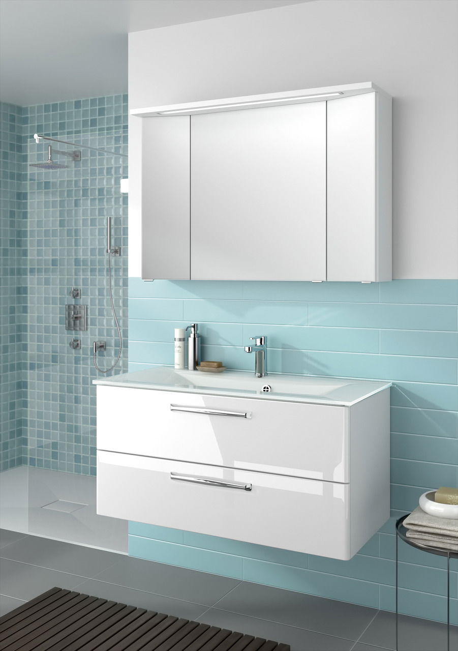 Moderner weißer Badblock mit zwei Schubladen und integriertem Waschbecken, frontal betrachtet, vor einer hellblauen gefliesten Wand.