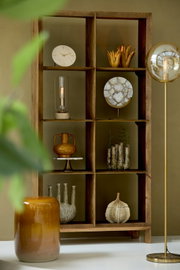 Houten plank met decoratieve voorwerpen van verschillende materialen, van voren gefotografeerd.